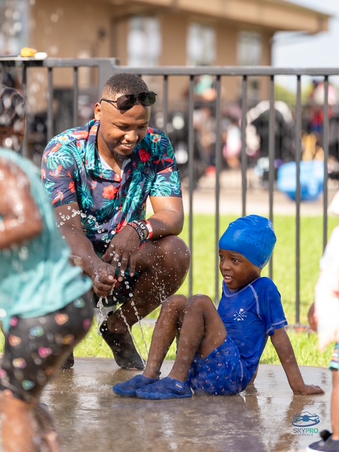 Dad playing in the splash pad with his son